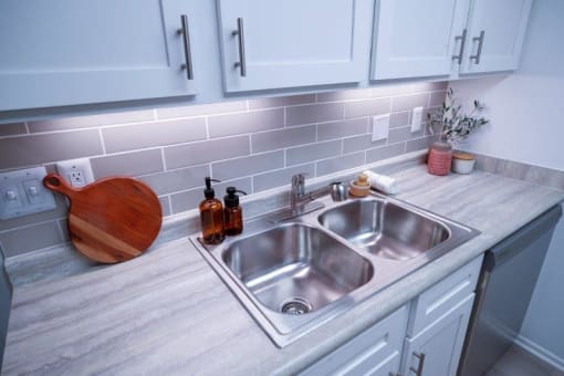 a stainless steel sink in a kitchen with white cabinets