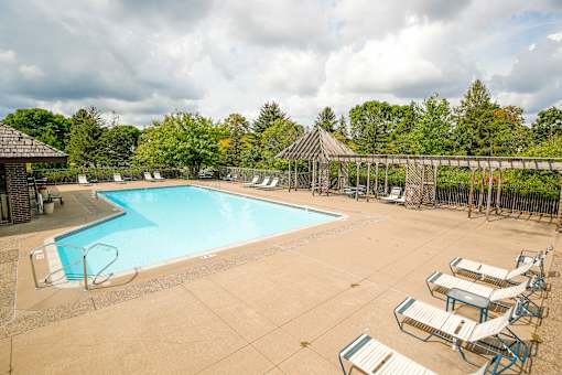 A large swimming pool surrounded by trees and a gazebo.