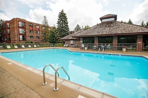 A large swimming pool in front of a building with a red brick exterior.
