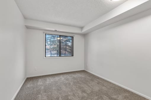 a bedroom with a large window and a carpeted floor