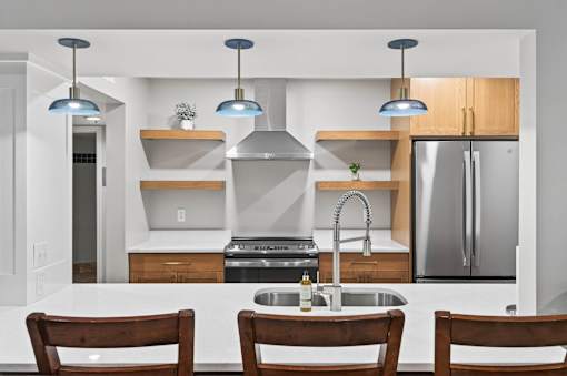 A modern kitchen with a sink, stove, and refrigerator.
