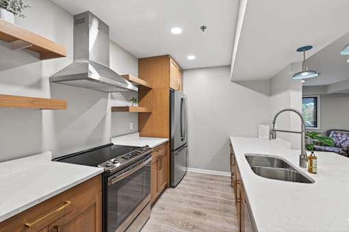 A modern kitchen with a stainless steel range hood and a double sink.