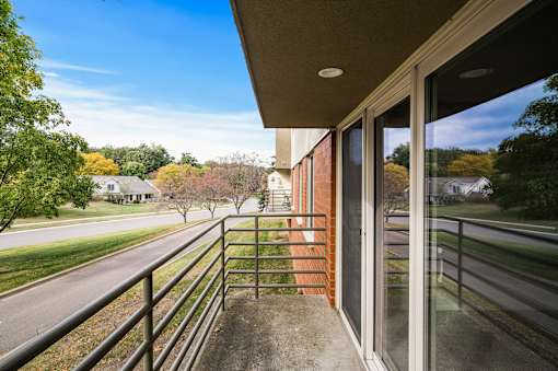 a balcony with a view of a street and some trees