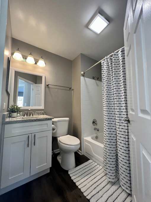 A white bathroom with a toilet, sink, and shower.