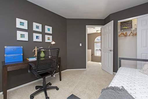 A room with a black chair and a desk with a blue box on it.