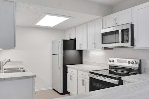 A kitchen with white cabinets and appliances.