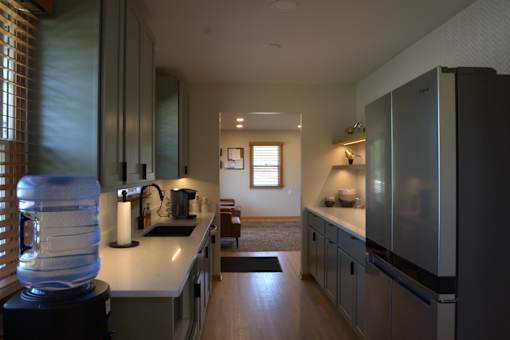 A kitchen with a white counter top and a water cooler.