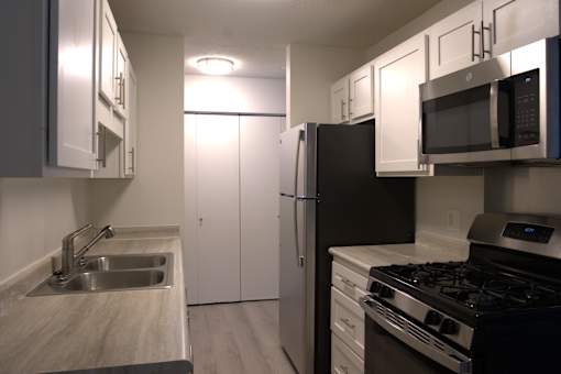 A kitchen with a black refrigerator, stove, and microwave.