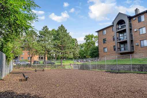 A playground with a slide and a building in the background.