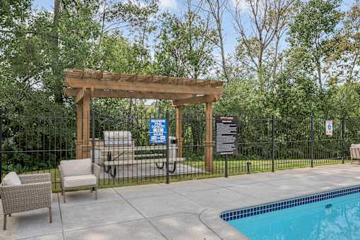 A pool area with a wooden pergola and a black fence.