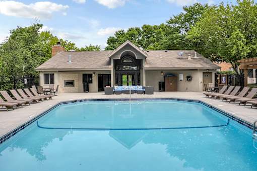 A pool in front of a house with a black fence.