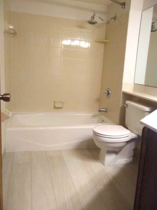 A white toilet sits in a bathroom next to a bathtub.