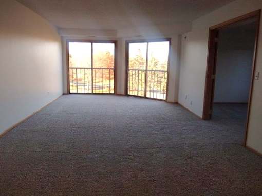 A room with carpeted floor and two sliding glass doors.