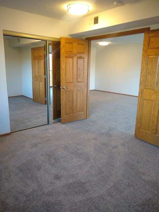 A room with carpeted floor and three doors.