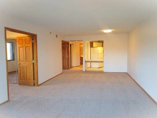 A room with a carpeted floor and a door on the left side.