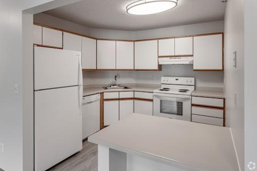 A white kitchen with a refrigerator, oven, and microwave.