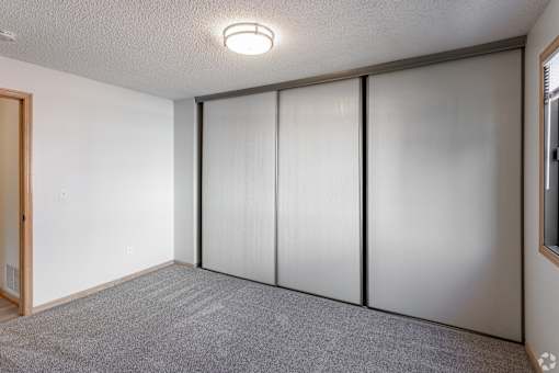 A room with a grey carpet and a white wall with a sliding door.