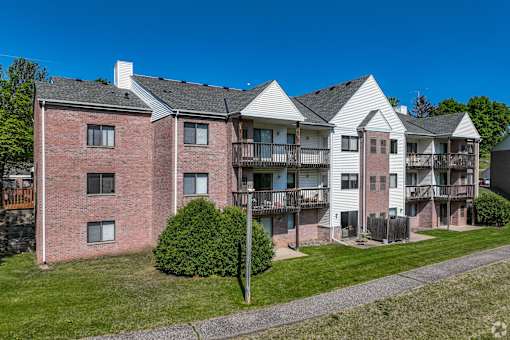 Apartment complex with red brick building and white building with balconies.