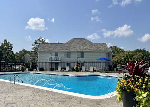 A pool in front of a house with a blue umbrella.