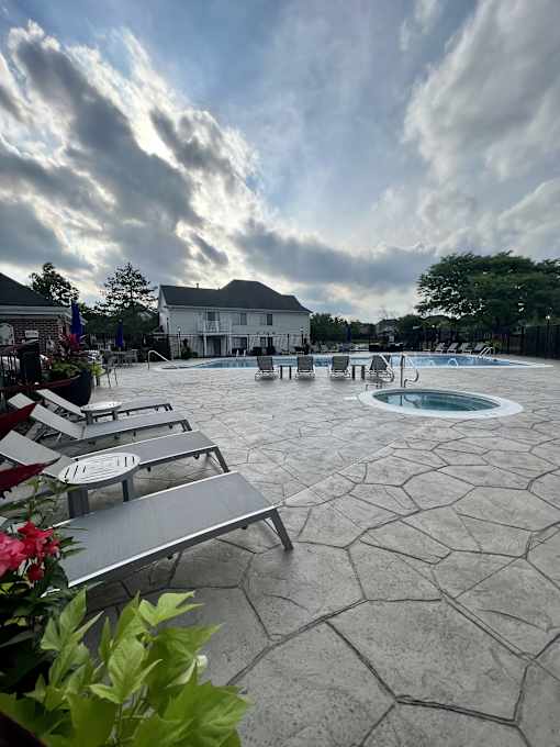 A pool area with a hot tub and lounge chairs.