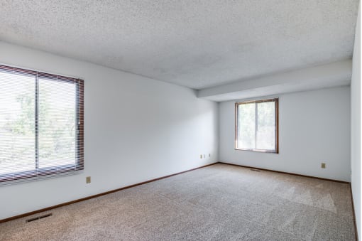 an empty living room with a large window and white walls