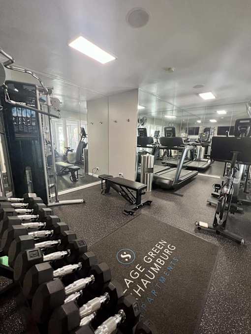 A gym with a row of dumbbells and a sign that says