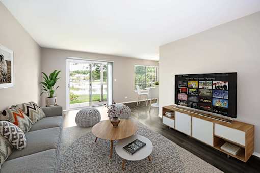 A modern living room with a grey couch, a wooden coffee table, and a flat screen TV.
