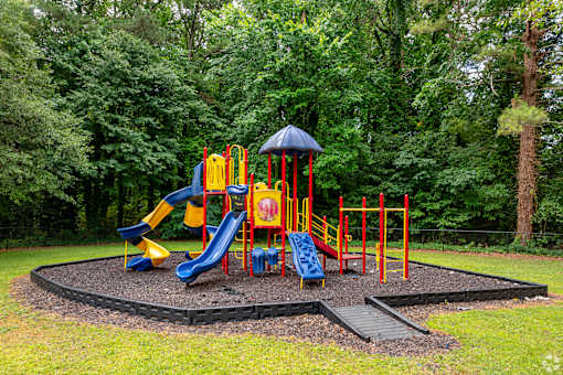 A playground with a yellow slide and a blue slide.