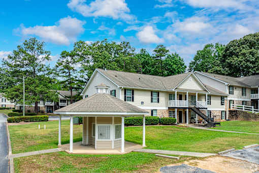 A house with a covered porch and a tree in the background.