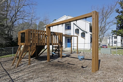 a backyard playground with a wooden playset and a swing set