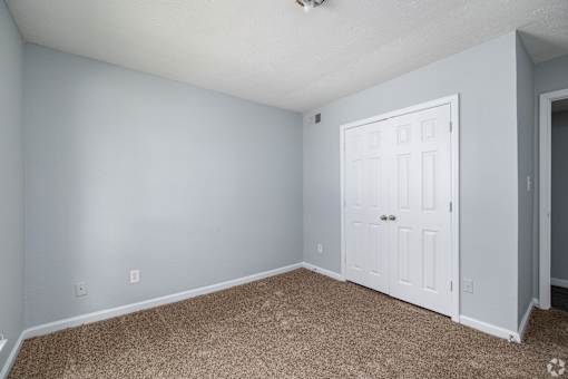 A room with a white door and carpeted floor.