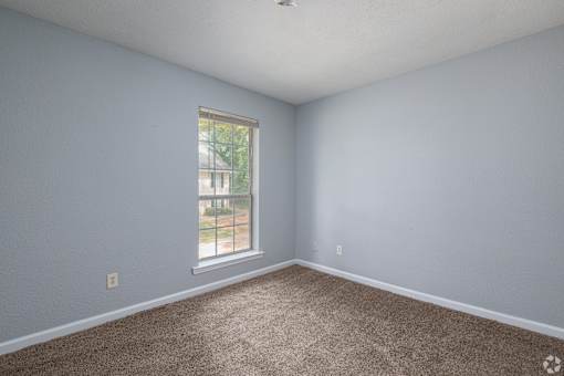 A room with a carpeted floor and a window.