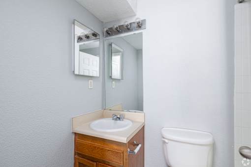 A bathroom with a sink, toilet, and mirror.