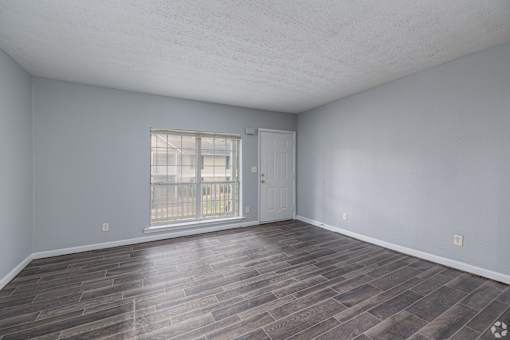 A room with a wooden floor and a sliding glass door.
