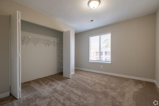 an empty living room with a closet and a window