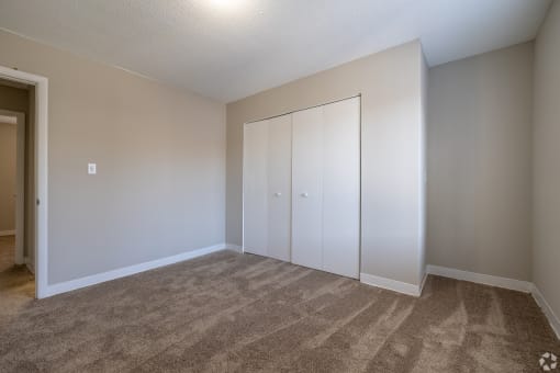 an empty room with carpet and white closet doors
