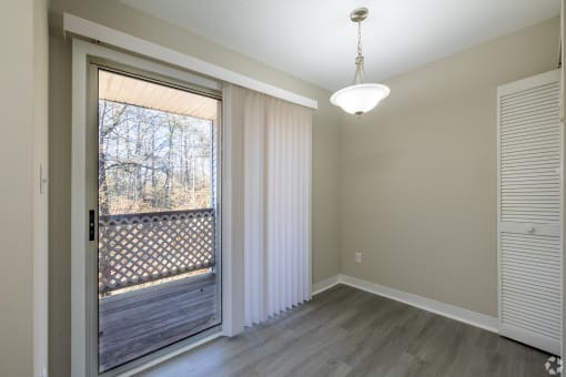an empty living room with a large window and a door to a balcony