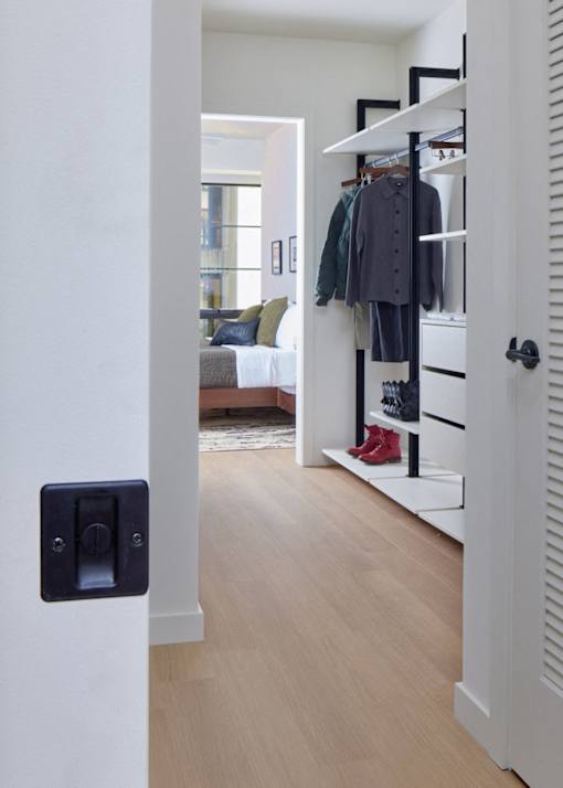A white door with a black handle is open to a hallway with a coat rack.