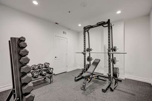 A black and white photo of a home gym with weights and exercise equipment.