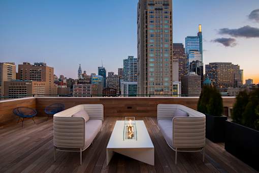 A rooftop patio with a table and chairs overlooking a city skyline at dusk.at 1600 Callowhill, Philadelphia Pennsylvania 