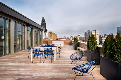 A patio with blue chairs and tables overlooks a city skyline.at 1600 Callowhill, Philadelphia, 19130