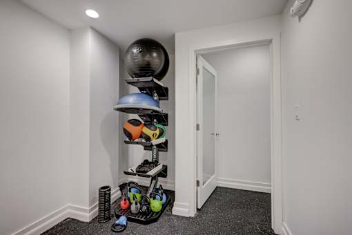 A room with a white door and a shelf with exercise equipment.