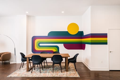 A dining room with a colorful mural on the wall.