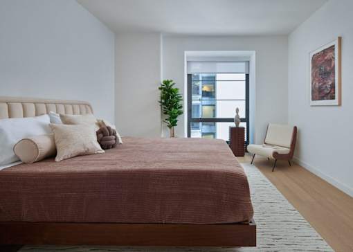 A bedroom with a large bed and a chair.