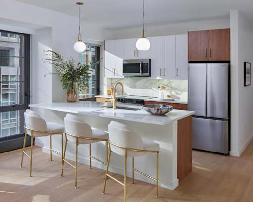 A modern kitchen with white and gold chairs.