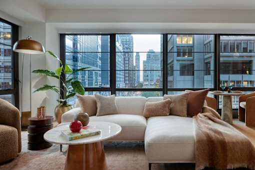 A living room with a white couch and a coffee table with a red apple on it.