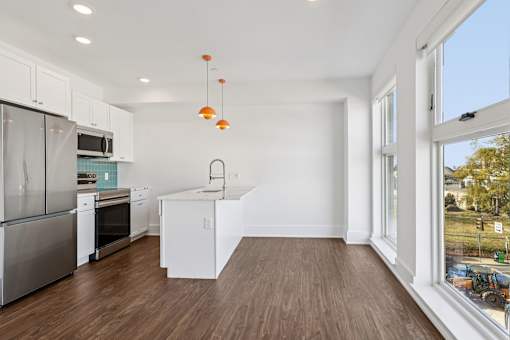 A kitchen with white cabinets and a wooden floor.