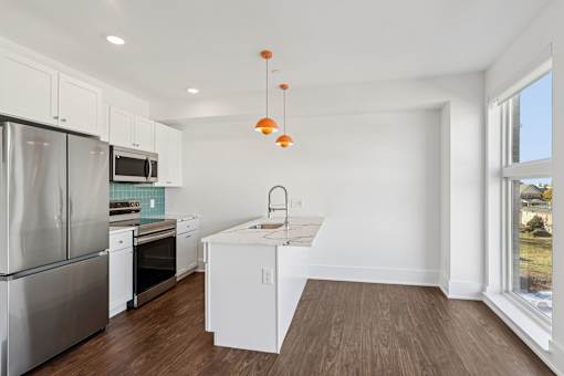 A kitchen with white cabinets and a stainless steel refrigerator.