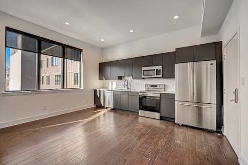 A modern kitchen with stainless steel appliances and wooden floors.