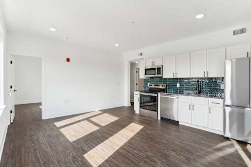 A kitchen with white cabinets and a wooden floor.